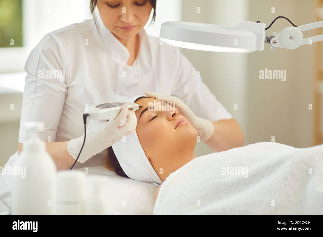 Frau Dermatologe tun Ultraschall-Gerät Gesichtsreinigung mit speziellen Maschine Für junge Frau Stockfoto