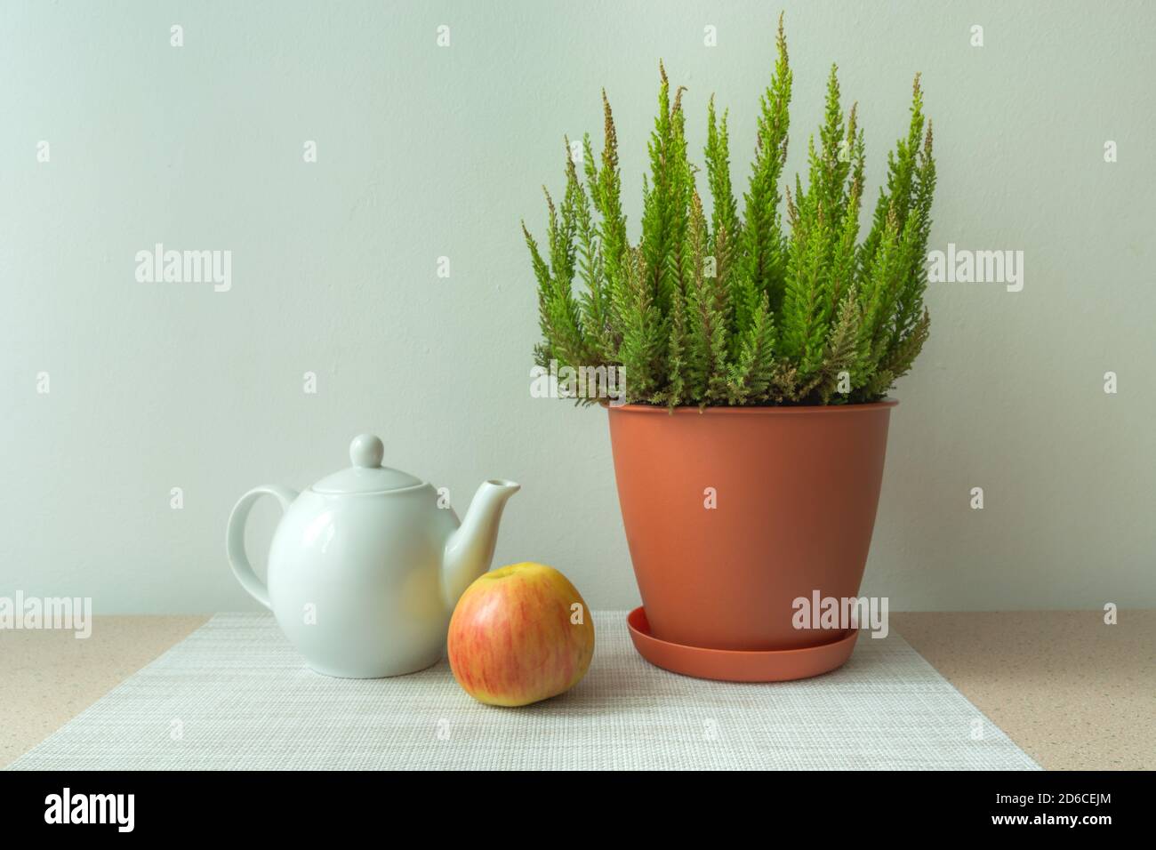 Weiße Porzellan Teekanne, ein Apfel und eine Blume in einem Topf Stockfoto