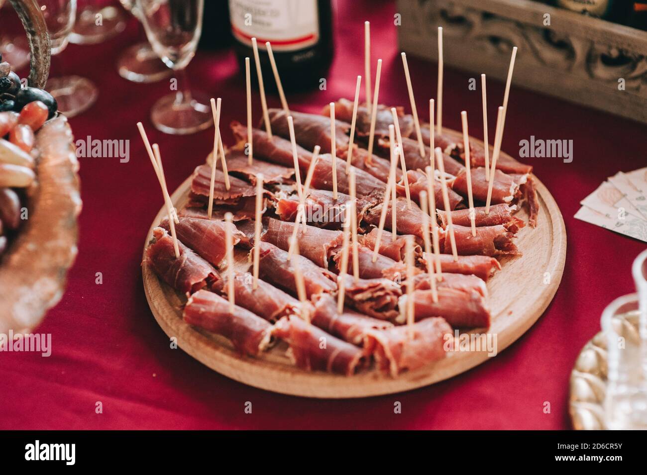 Seitenansicht einer runden Holzplatte mit geschnittenen und verdrehten Fleischstücken auf Spieße. Catering. Stockfoto