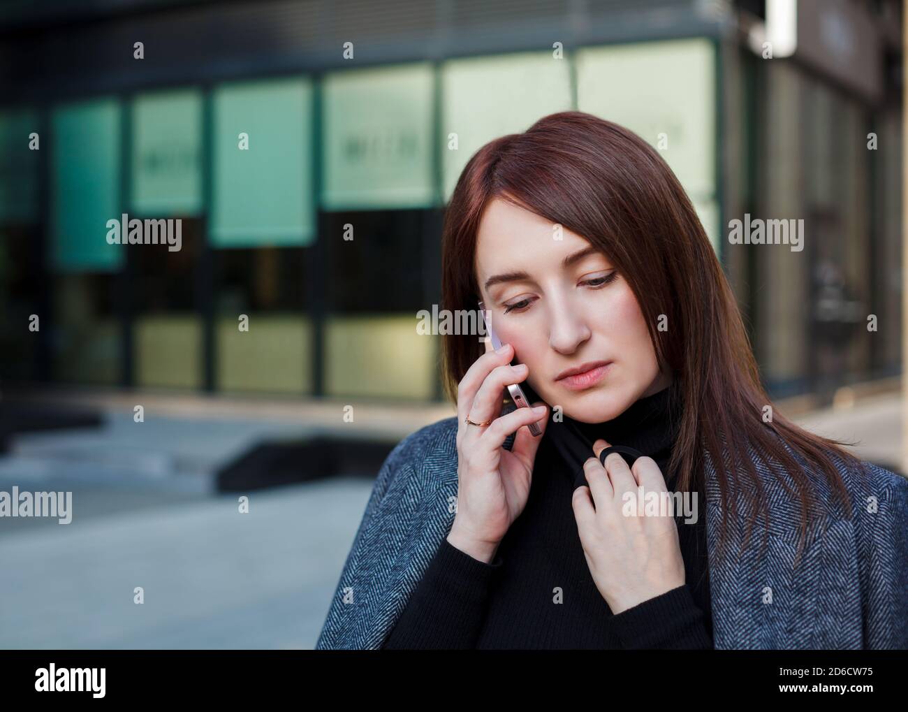 Traurige Frau schaut auf den Boden und telefoniert in der Innenstadt. Business Frau Stress Konzept. Stockfoto