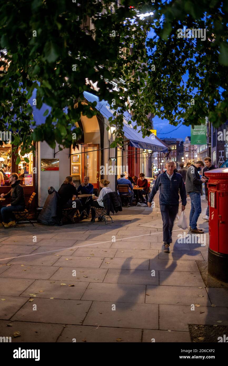 Die Kunden genießen ein gesellschaftlich distanziertes Getränk und ein Plauderei an Tischen auf der Straße vor einem öffentlichen Haus im West End in Londons Covent Garden. Wie viele Roa Stockfoto