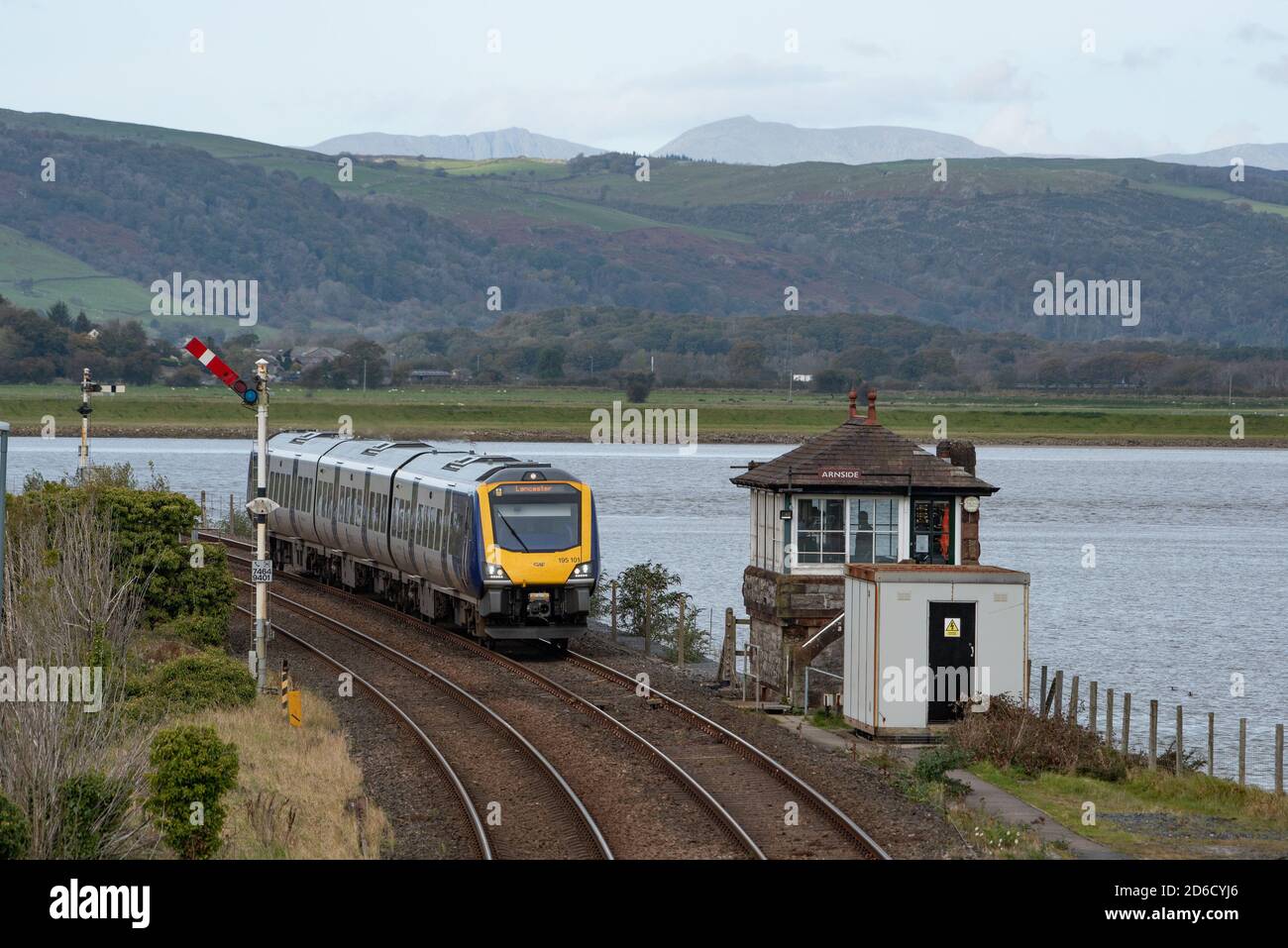 Ein Zug, der die Signalbox des Arnside Bahnhofs, Cumbria, Großbritannien, passiert Stockfoto