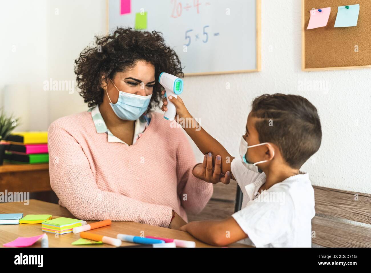 Kinder-Check-up Temperatur auf Lehrer im Klassenzimmer während Corona-Virus Pandemie - Gesundheitsmedizin und Bildungskonzept Stockfoto