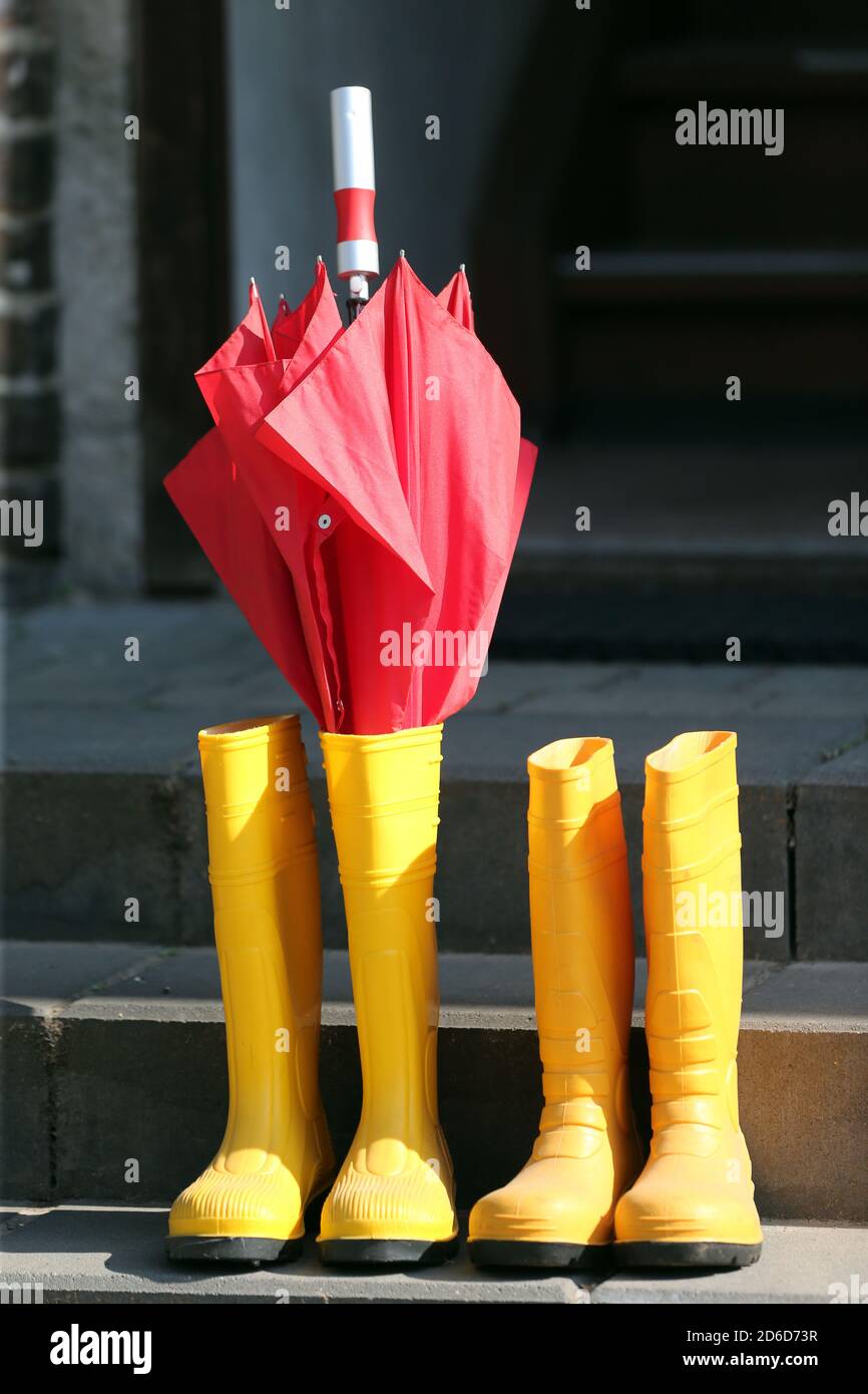 09.04.2020, Neuenhagen, Brandenburg, Deutschland - Regenschirm und Gummistiefel stehen auf einer Treppe im Sonnenschein. 00S200409D036CAROEX.JPG [MODELL RELEA Stockfoto
