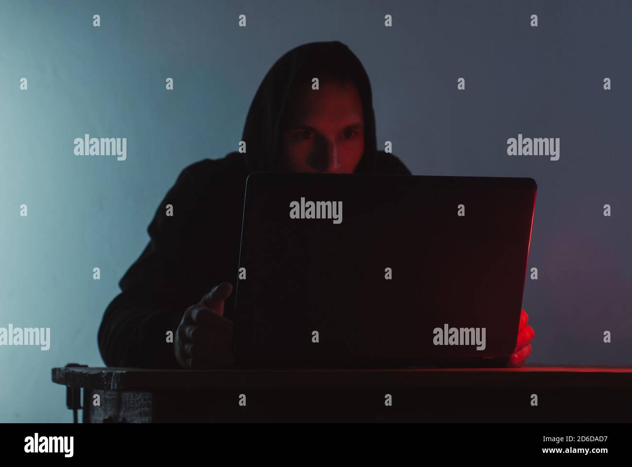 Der Mann mit Kapuze arbeitet an einem Laptop, Stockfoto