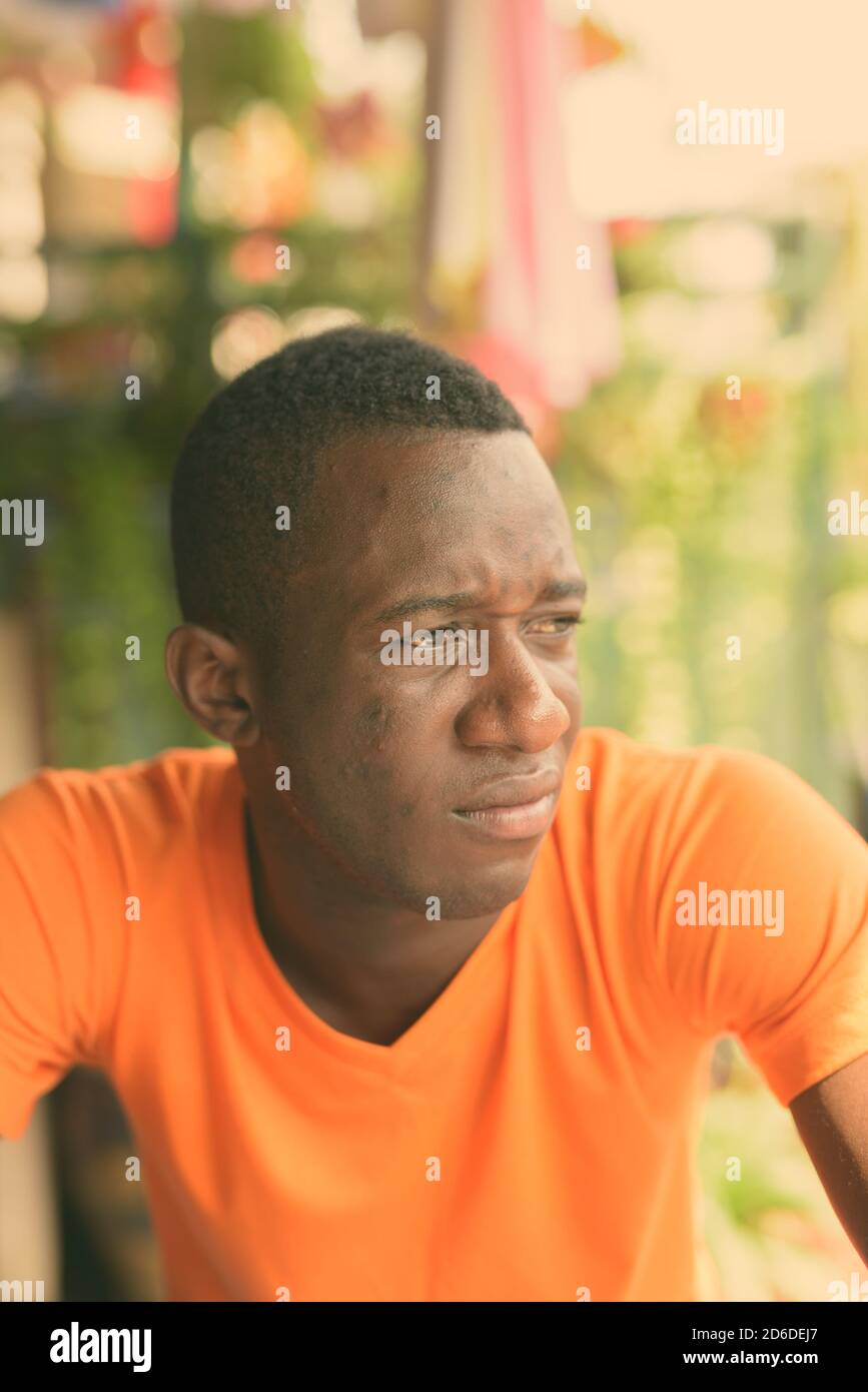 Gesicht der jungen schwarzen afrikanischen Mann zu denken, während der Abstand in den ruhigen Garten im Freien suchen Stockfoto