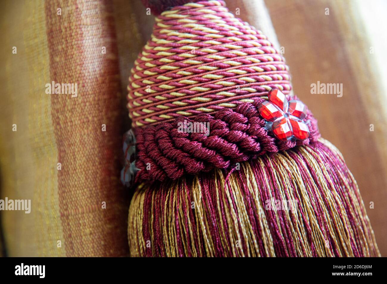 Nahaufnahme von ausgefallenen Vorhang Quaste auf einem gebunden zurück Vorhang in Gold und Karmesin Farben. Stockfoto