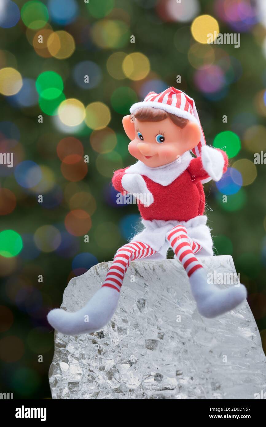 Bokeh-Aufnahme im Urlaub. Ein Elf auf einem Eisblock mit einem beleuchteten Baum im Hintergrund Stockfoto