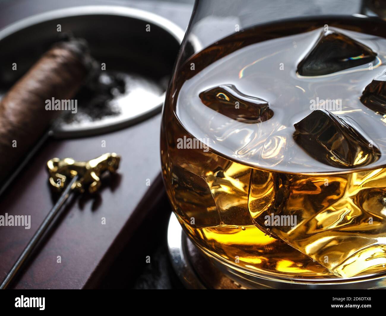Whisky auf den Felsen und eine Zigarre in einem Aschenbecher Auf einer schwarzen Schieferfläche Stockfoto