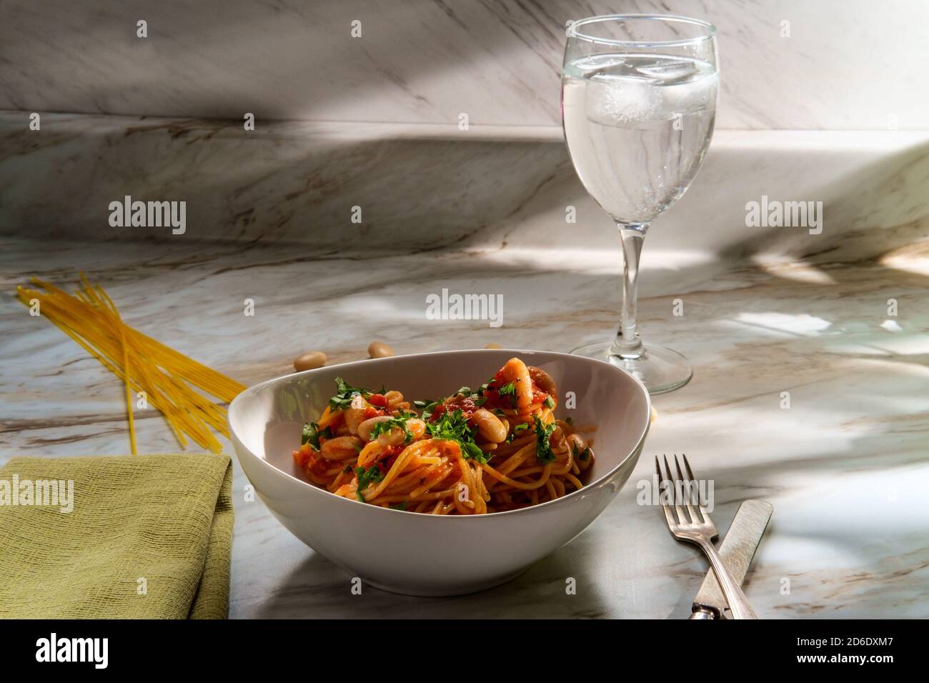 Italienische würzige Spaghetti Pasta all’Arrabbiata mit Cannellini Bohnen in Sonnenlicht aus dem Fenster Stockfoto