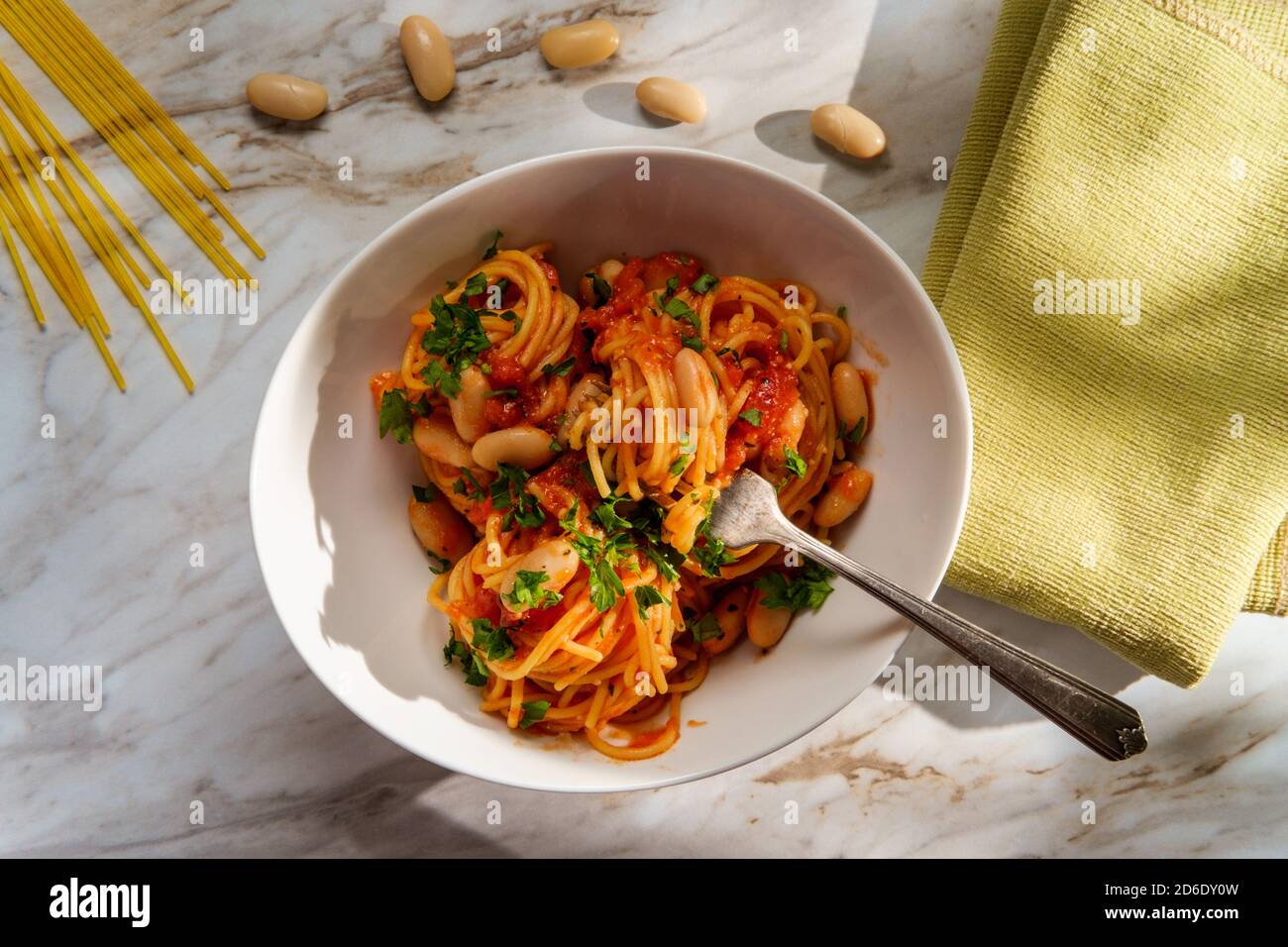 Italienische würzige Spaghetti Pasta all’Arrabbiata mit Cannellini Bohnen in Sonnenlicht aus dem Fenster Stockfoto