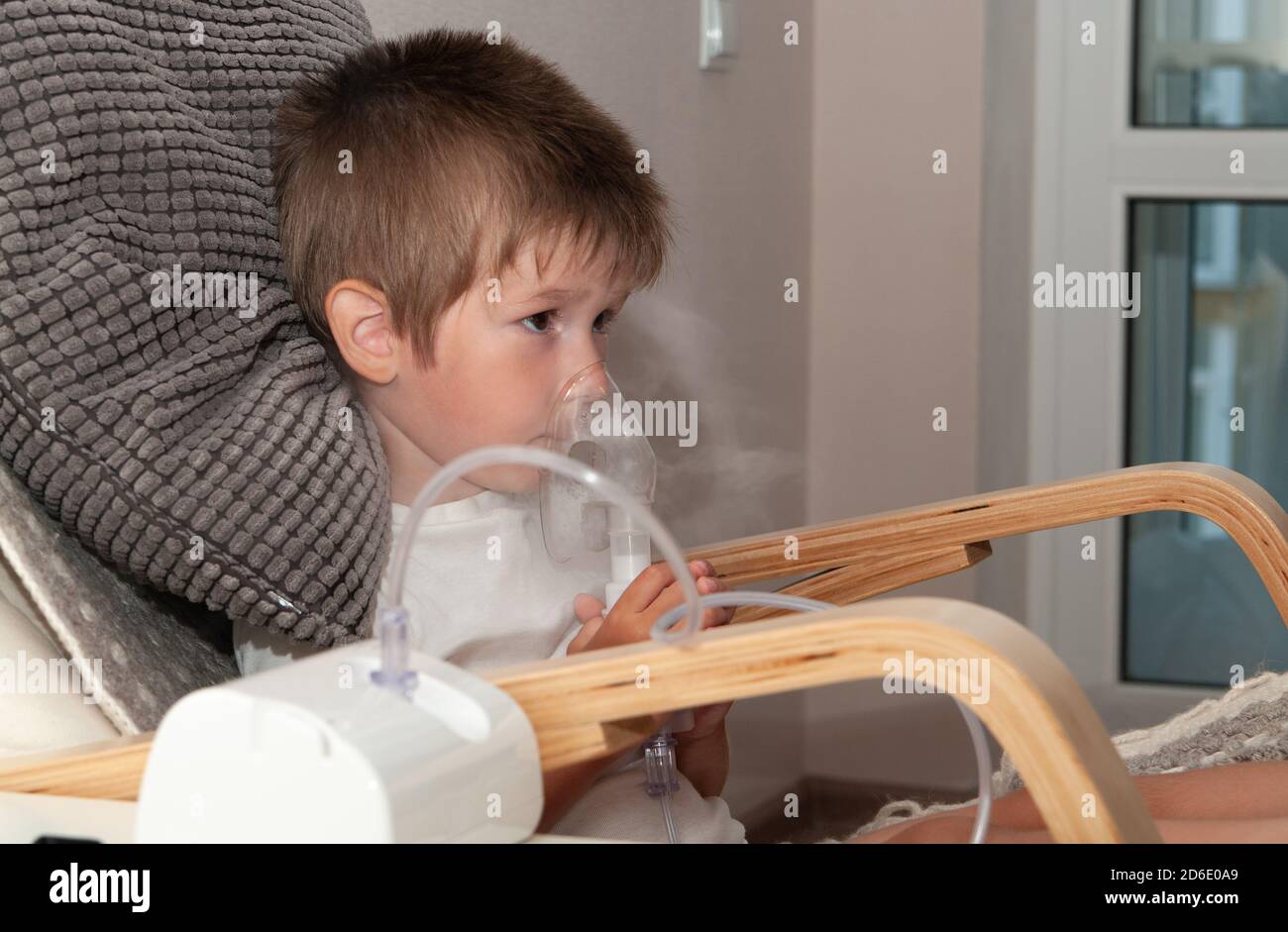 Kleiner kranker Junge mit Vernebler Maske macht Inhalation, Atemwegsprozedur durch Lungenentzündung oder Husten für Kind zu Hause. Stockfoto