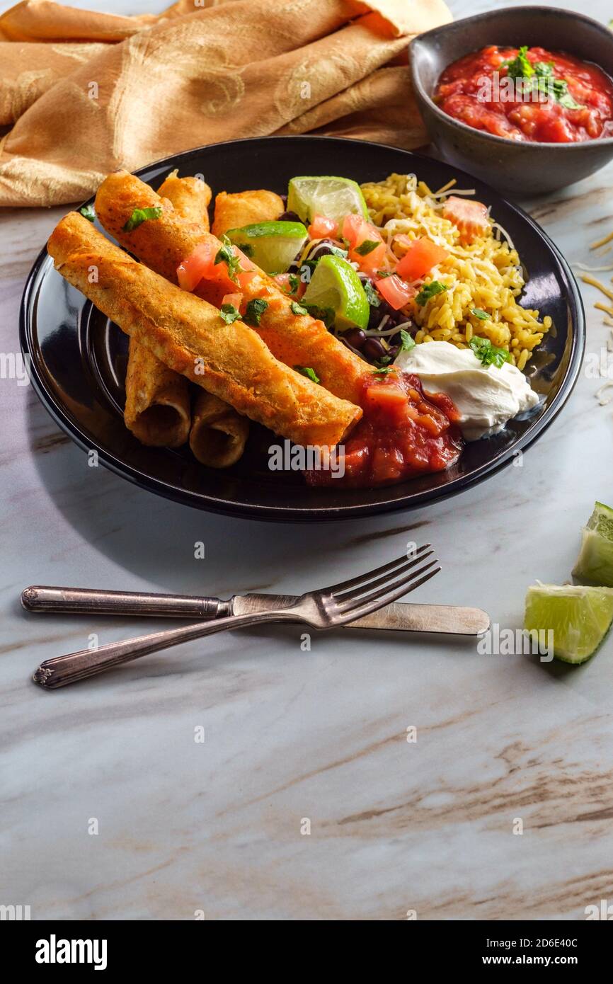 Mexikanisch gerolltes Taco Huhn und Käse Taquitos mit Reis und schwarzen Bohnen Stockfoto