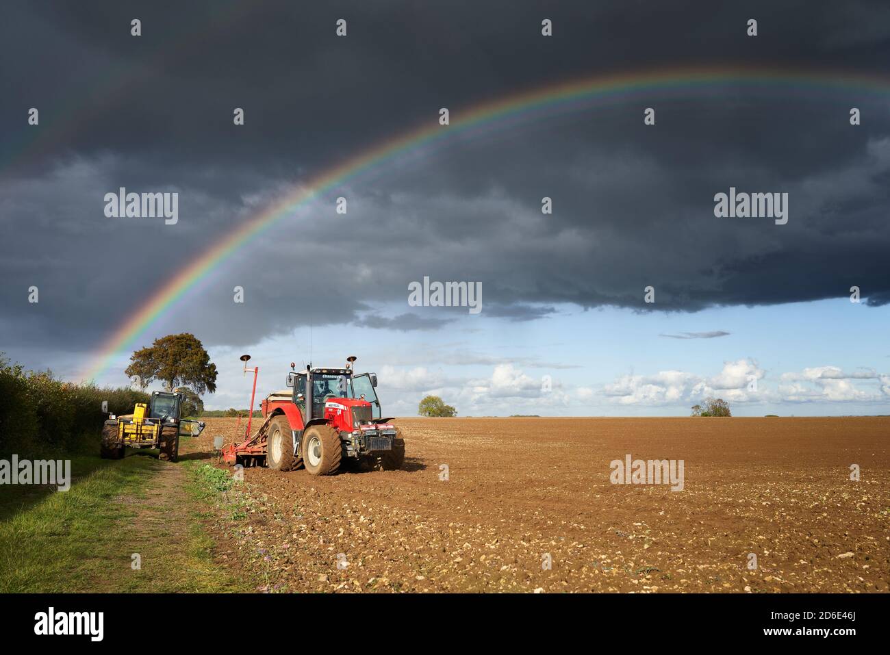 Double Regenbogen über Traktor und landwirtschaftliche Landmaschinen in einem Lincolnshire Feld beim Pflanzen oder Saatbohren Stockfoto
