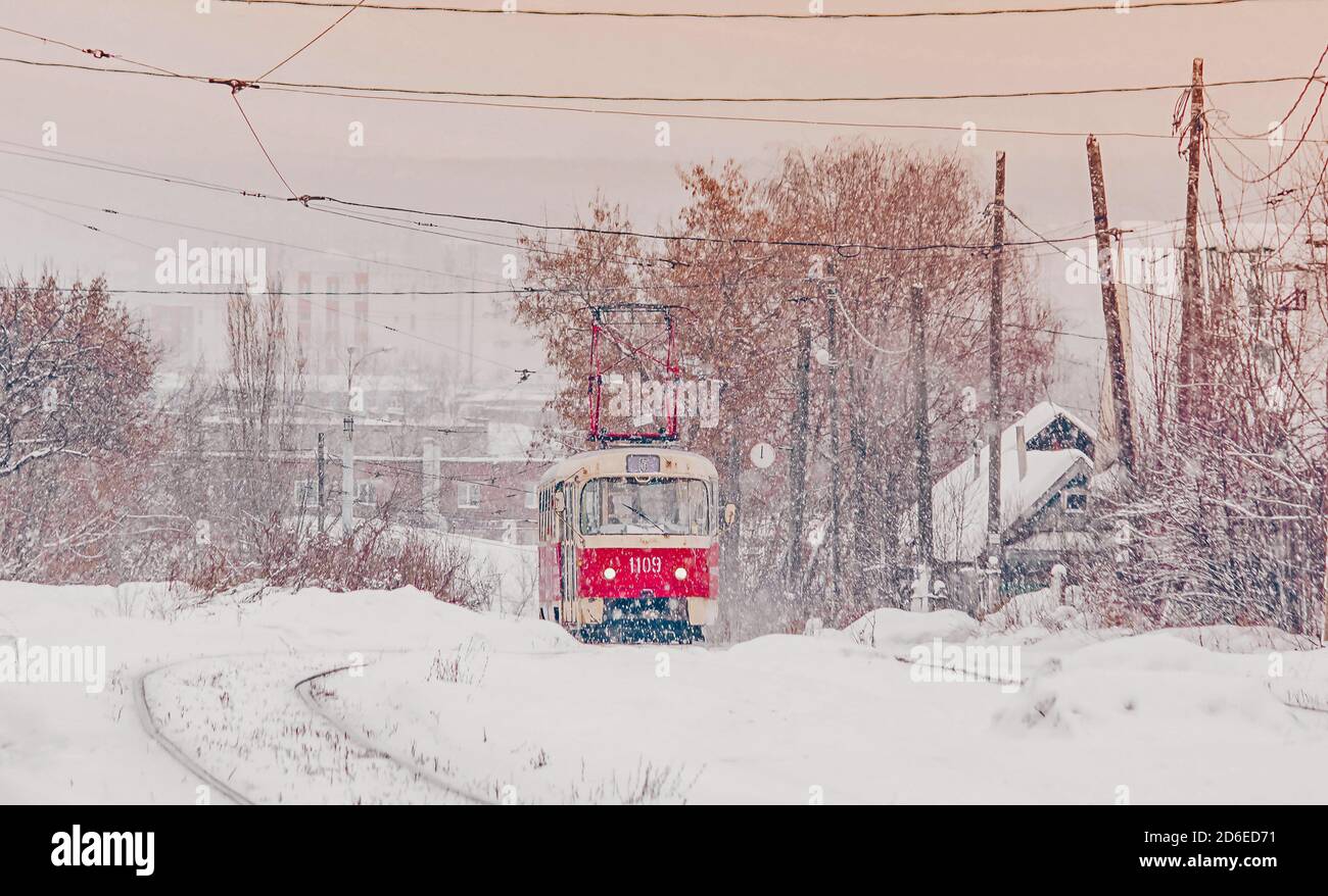 Rote nostalgische Straßenbahn fährt durch den Winter. Straßenbahn und Straßenbahnlinien in Russland im Winter mit Schnee Stockfoto