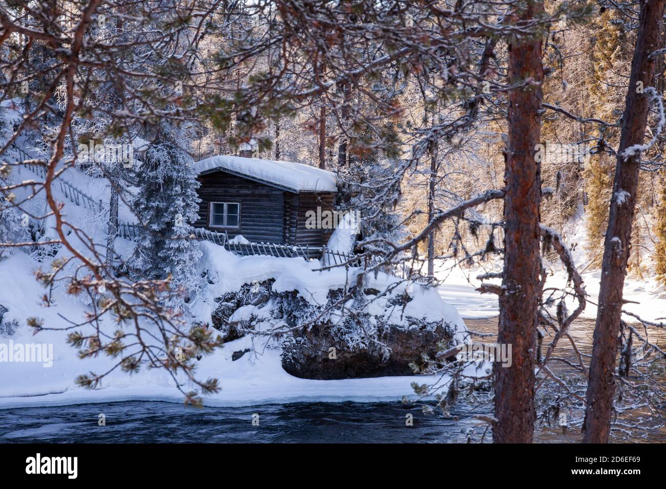 Eine kleine gemütliche Winterhütte am Fluss im finnischen Taigawald, Nordeuropa. Stockfoto