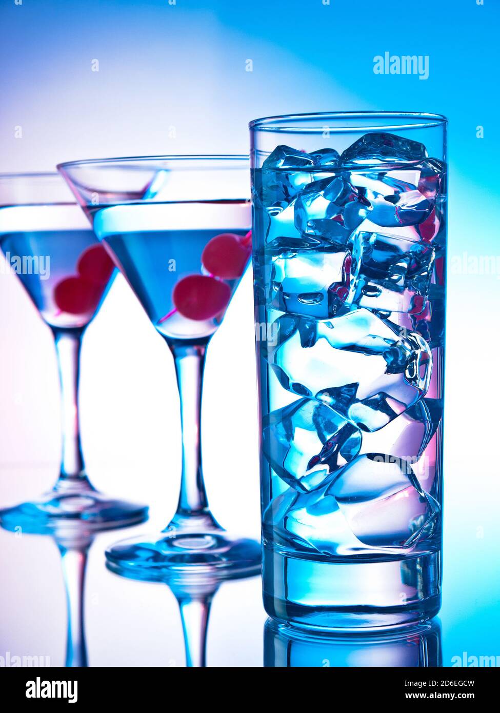Zwei Gläser martini mit roten Kirschen und ein Glas Von klarem Cocktail Stockfoto