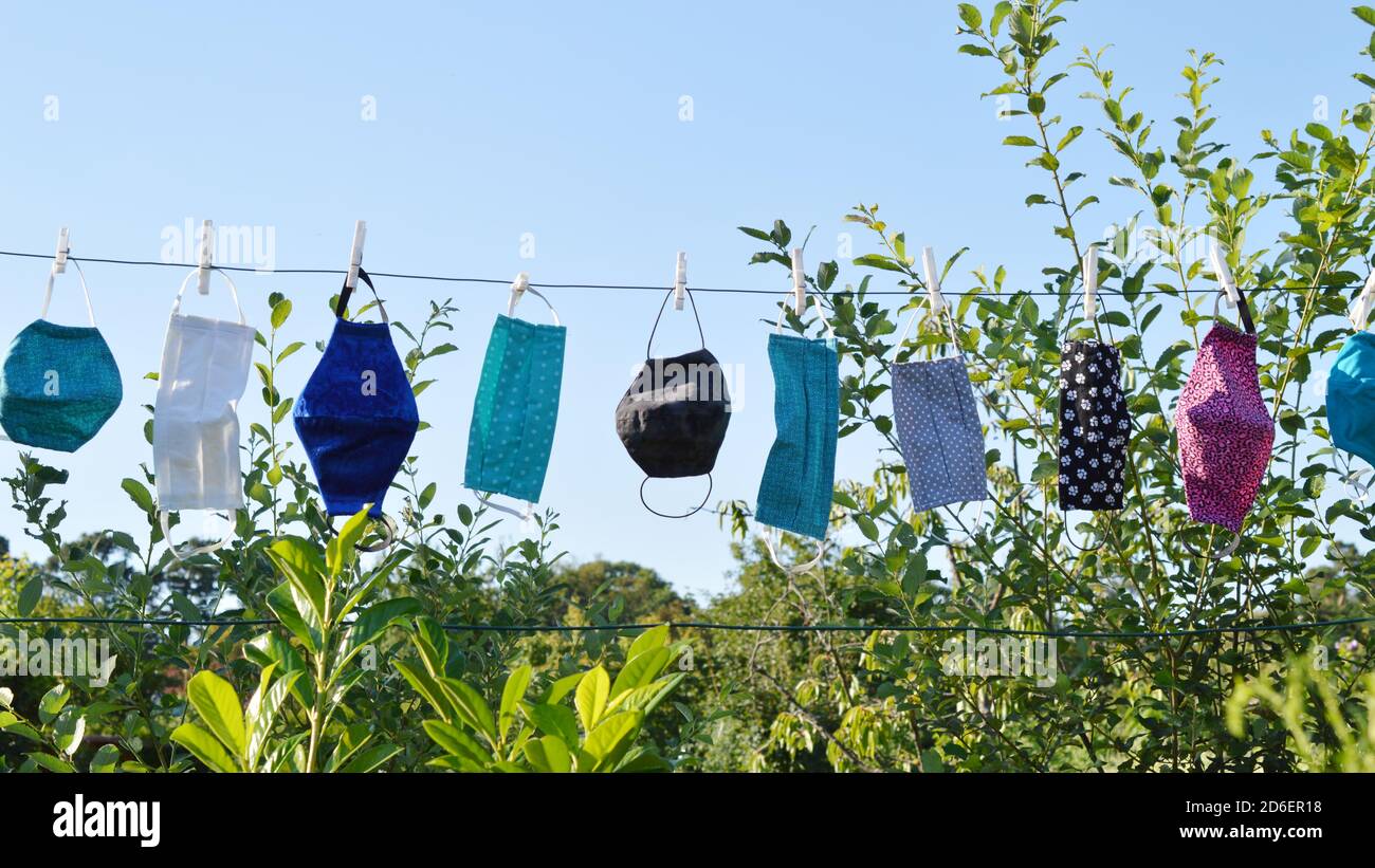 Viele verschiedene bunte selbst gemachte Corona Gesichtsmasken Aus Stoff hängen an einer Wäscheleine zum Trocknen Stockfoto