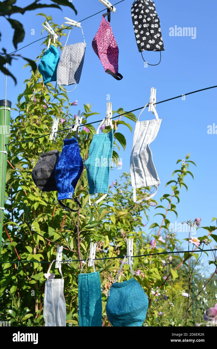 Viele verschiedene bunte selbst gemachte Corona Gesichtsmasken Aus Stoff hängen an einer Wäscheleine zum Trocknen Stockfoto