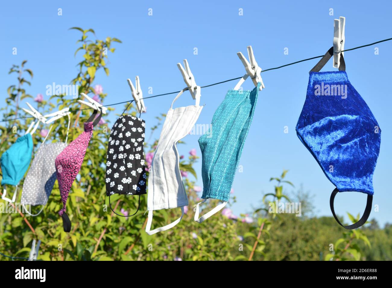 Viele verschiedene bunte selbst gemachte Corona Gesichtsmasken Aus Stoff hängen an einer Wäscheleine zum Trocknen Stockfoto