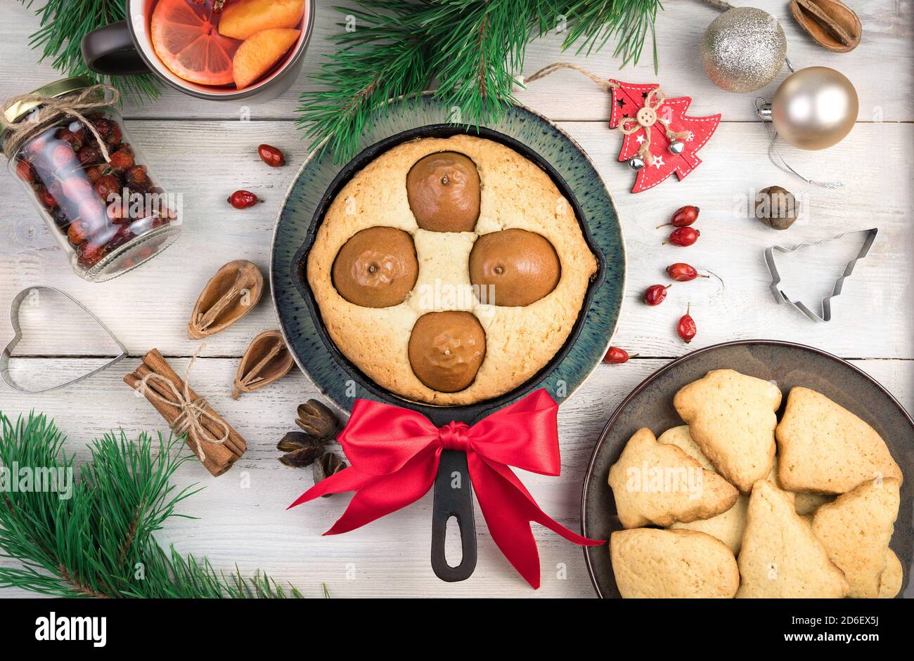 Birnenkuchen mit roter Weihnachtsschleife, Kekse und Glühwein auf hellem Holzhintergrund. Stockfoto