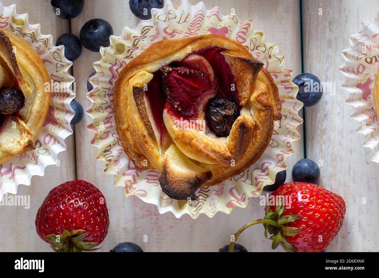 Tartlet mit Erdbeeren, Äpfeln, Heidelbeeren und Zimt auf Holzgrund. Frisches und gebackenes Obst. Stockfoto
