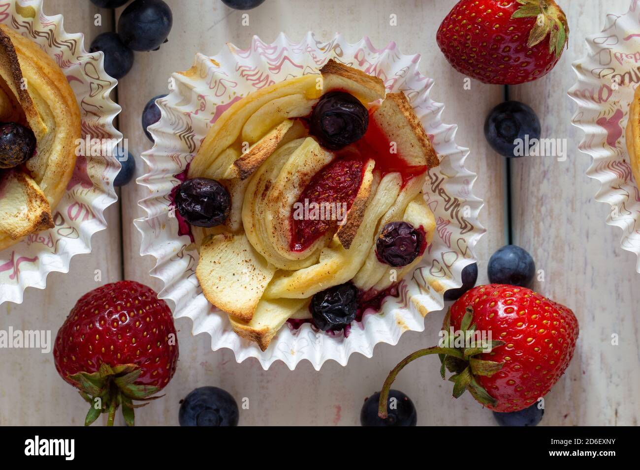 Tartlet mit Erdbeeren, Äpfeln, Heidelbeeren und Zimt auf Holzgrund. Frisches und gebackenes Obst. Stockfoto