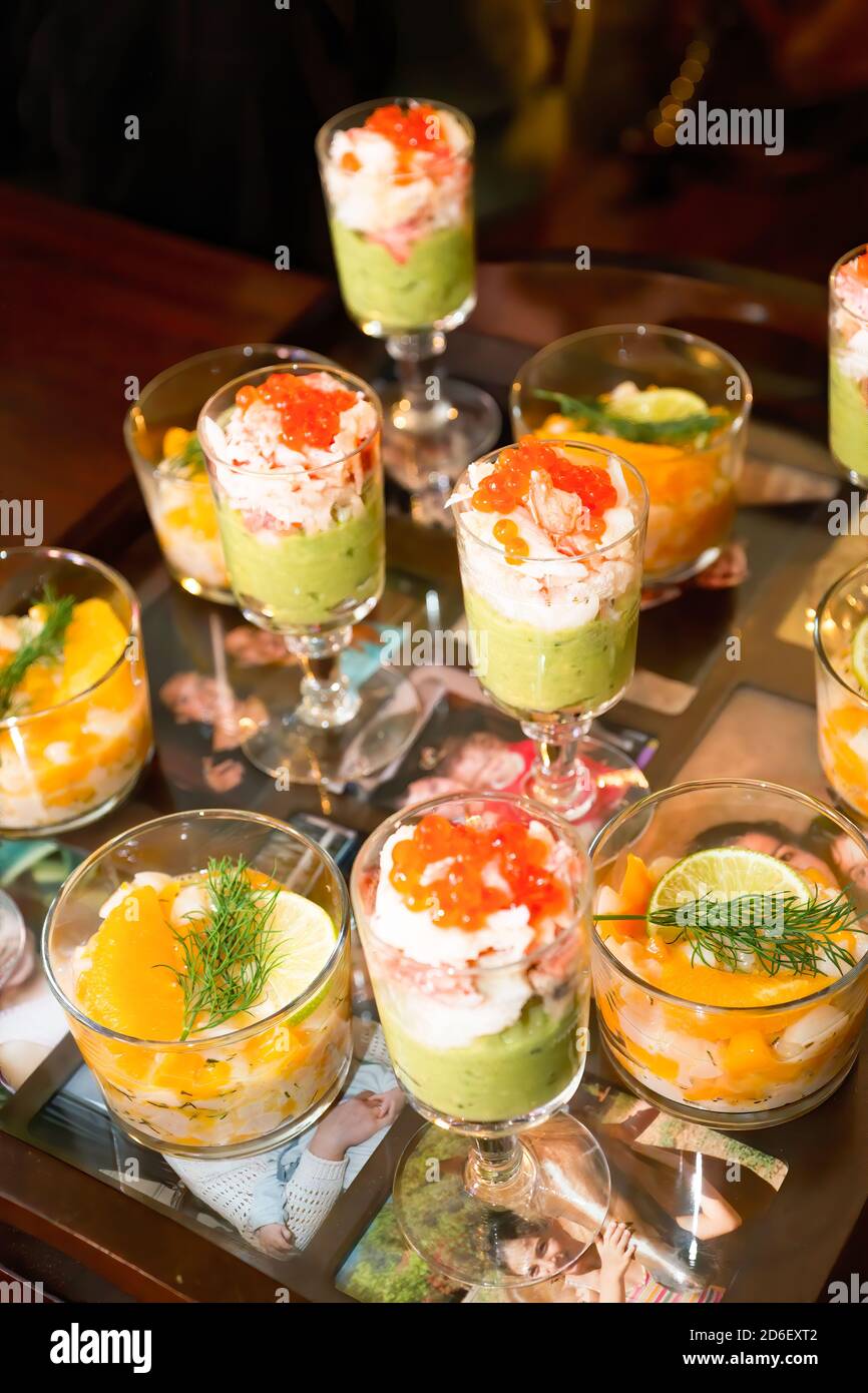 Teller mit Werrinen mit Avocado-Creme, Garnelen, Lachsrogen, Jakobsmuscheln (Pecten maximus), Mango, Orange, Limette und Dill. Stockfoto