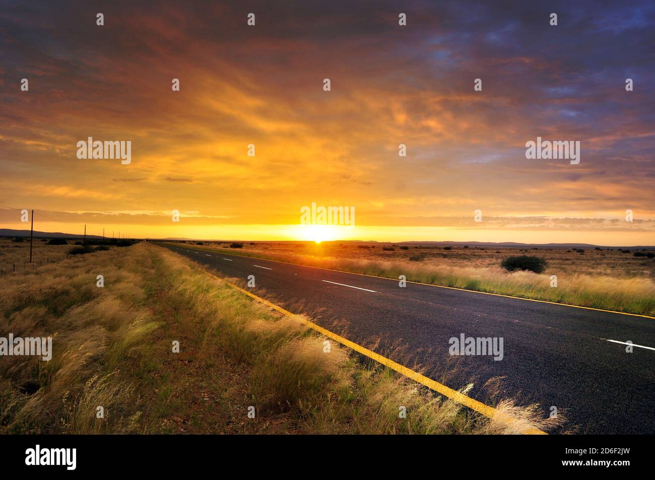 Sonnenaufgang über dem weiten Grasland und der Straße, Südafrika Stockfoto