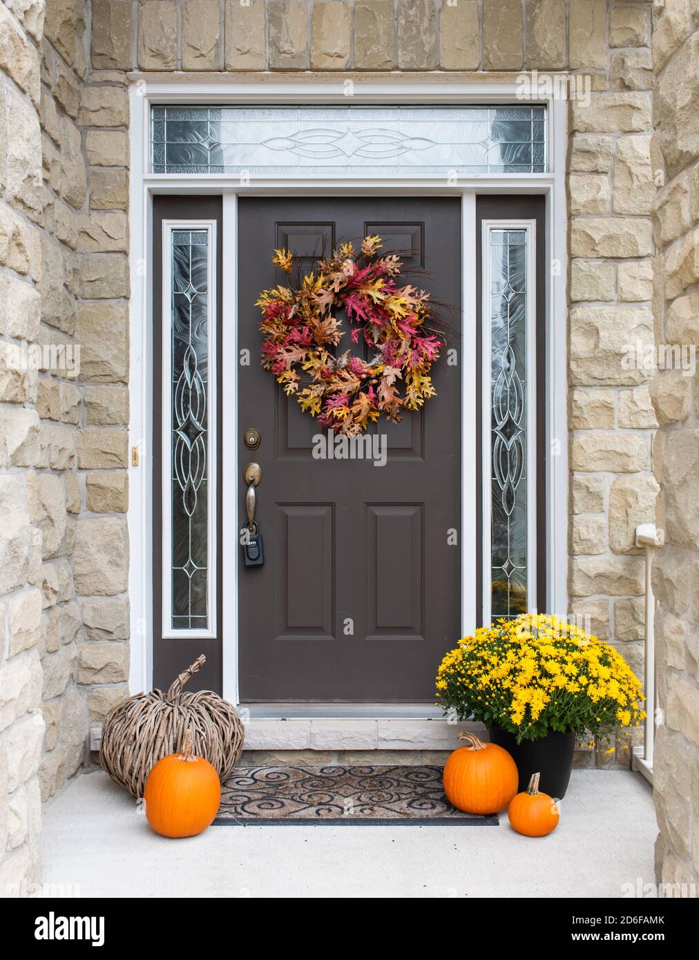 Vordertür des Hauses dekoriert für Herbst mit Blumen und Kürbissen. Stockfoto