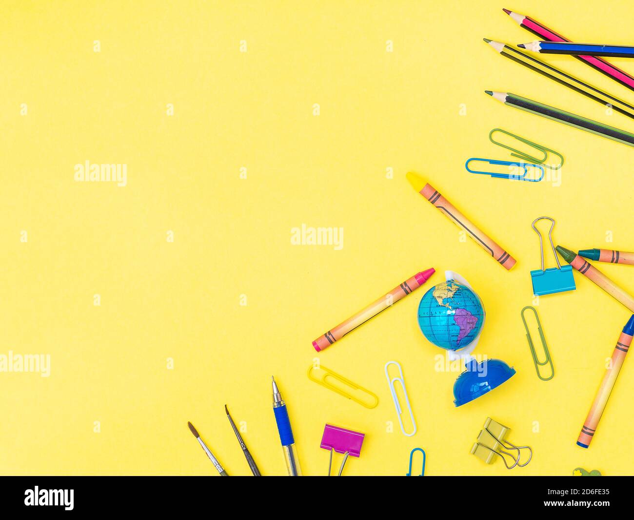 Zurück zur Schule, Bildungskonzept. Mehrfarbige Schreibwaren Werkzeuge Kreide, Schere, Globus, Büroklammern, Radiergummi, Stift, Bleistift isoliert auf gelb Farbe Bac Stockfoto