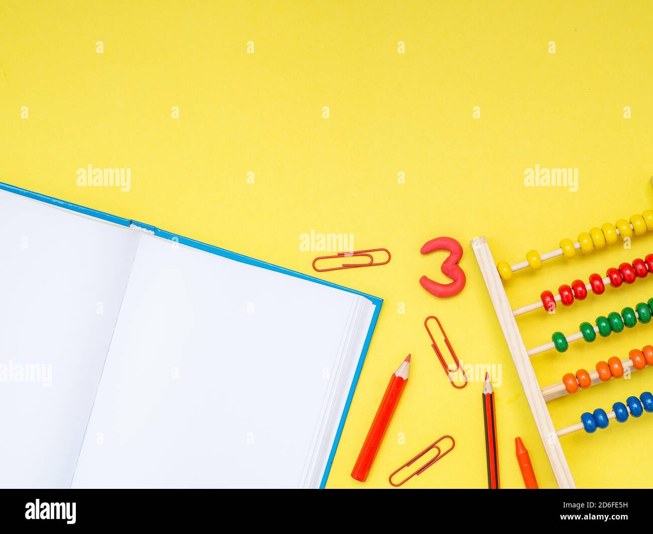 Zurück zur Schule, Bildungskonzept. Weißes Notizbuch mit Schulwerkzeugen, Büroklammern, Zahlen, Bleistiften, Kugelschreiber und Taschenrechner isoliert auf gelbem studi Stockfoto