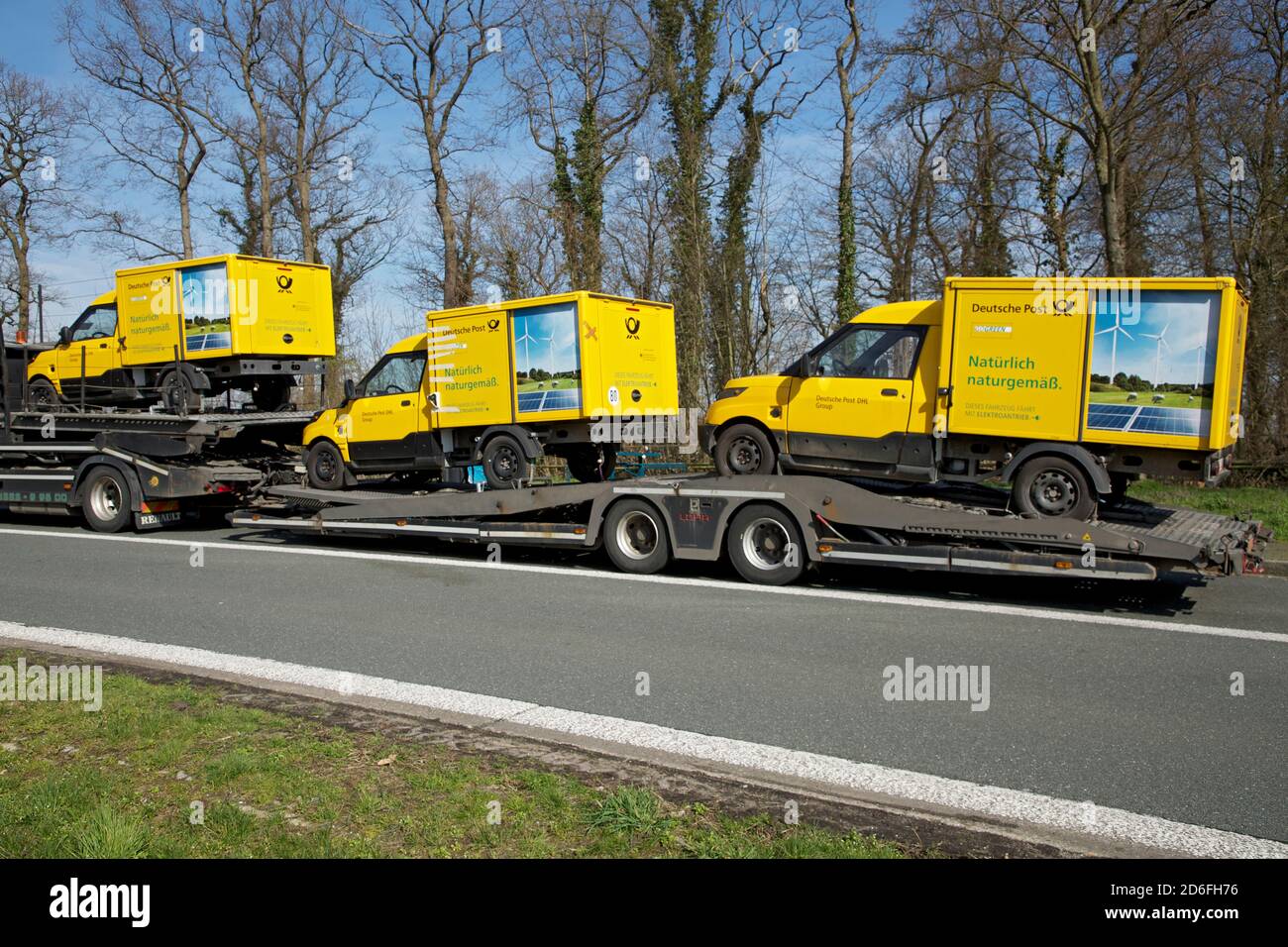 Defekte Elektrofahrzeuge der Deutschen Post auf einem LKW-Anhänger. Stockfoto