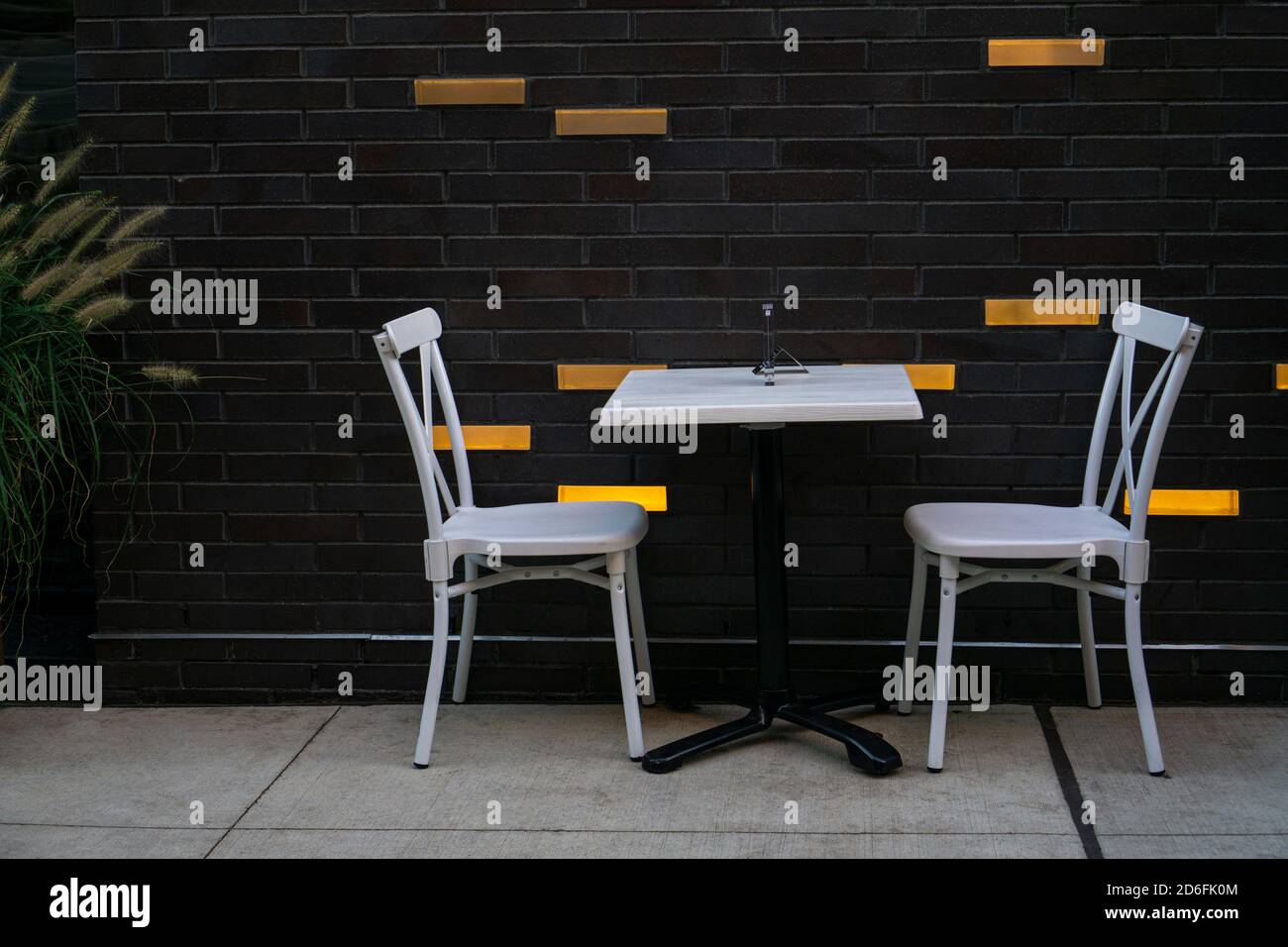 Ein Tisch und weiße Stühle für zwei Personen Unter sozialen Distanzierungsregeln während der covid-19 Pandemie bei a Straßencafé Stockfoto