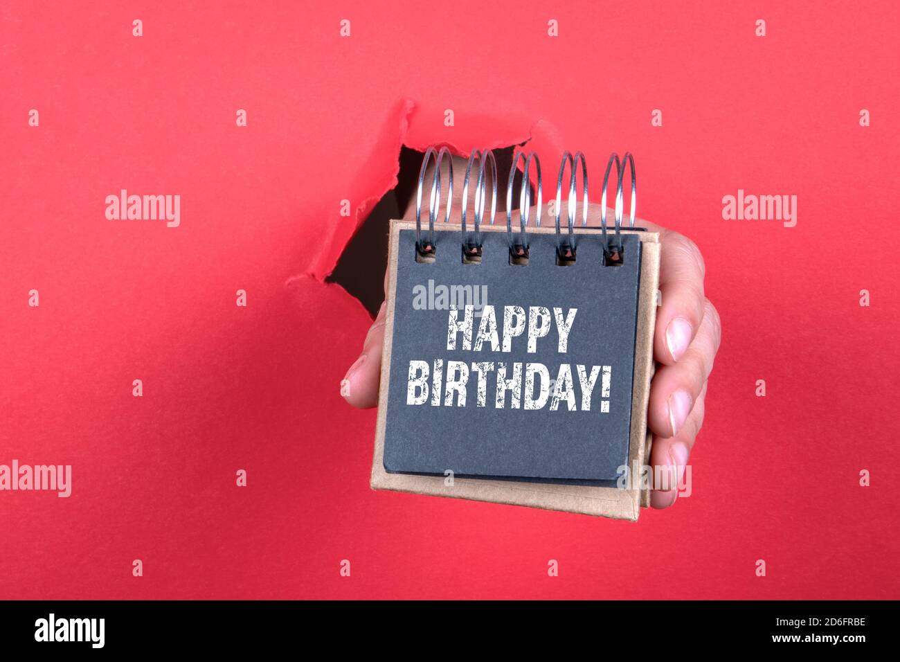 ALLES GUTE ZUM GEBURTSTAG! Notizbuch in einer Frauenhand auf rotem Hintergrund. Stockfoto