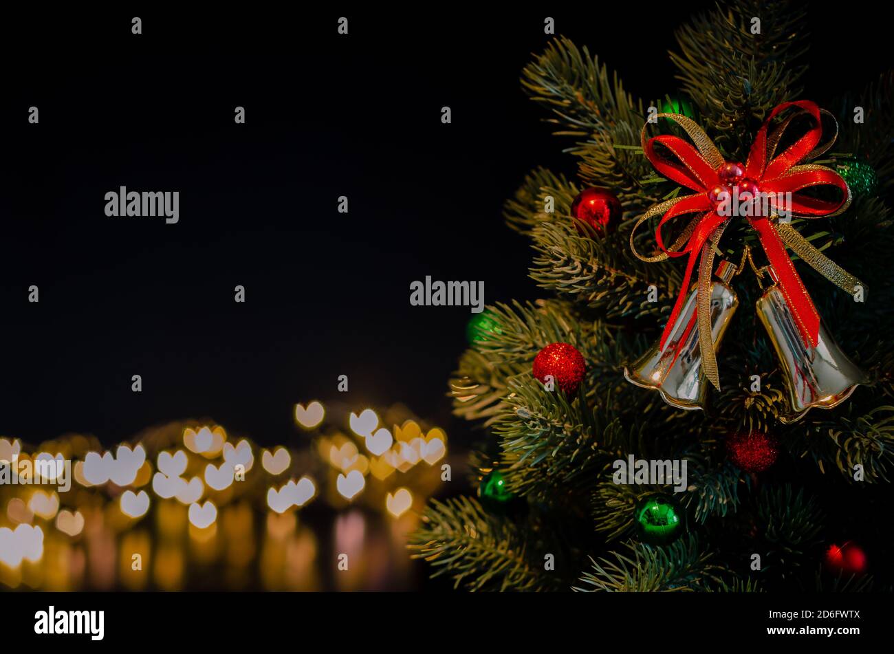Die Glocke Ornamente schmücken auf Weihnachtsbaum mit Liebe Form Bokeh Lichter Hintergrund. Weihnachts- und Neujahrskonzept. Stockfoto