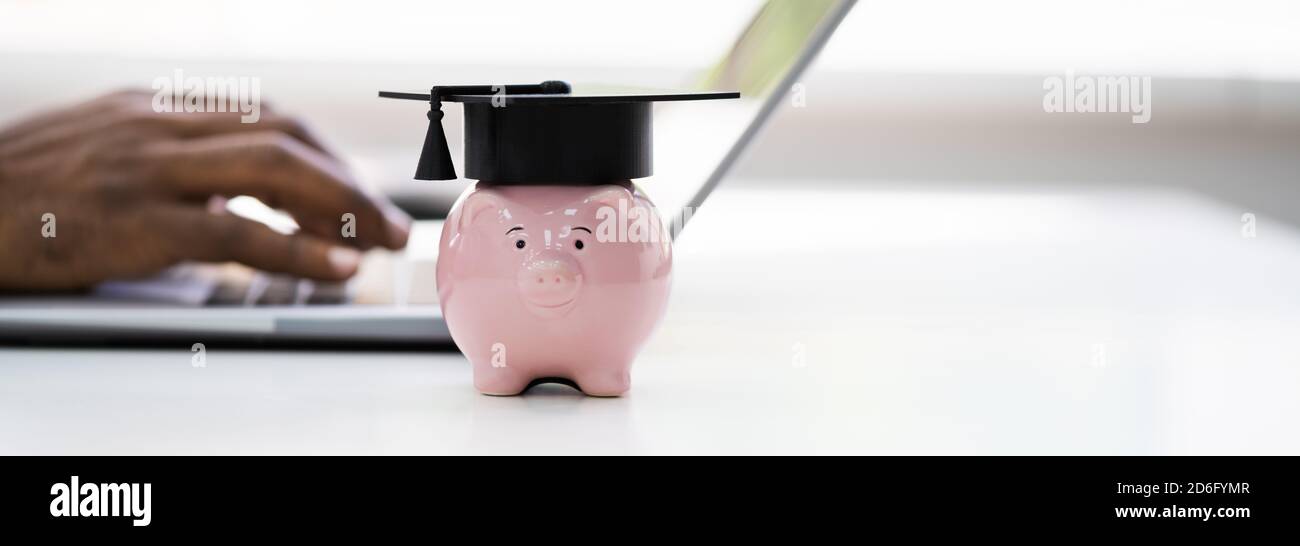 Universität Graduation Hat Auf Piggy Bank In Der Nähe Laptop-Computer Stockfoto