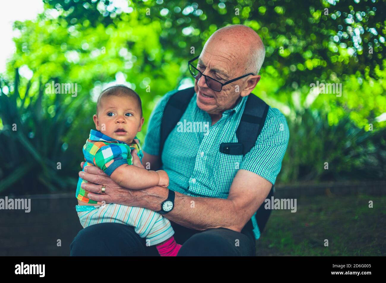 Ein Großvater hält sein Enkelkind im Freien in einem Kleine Stadt Stockfoto