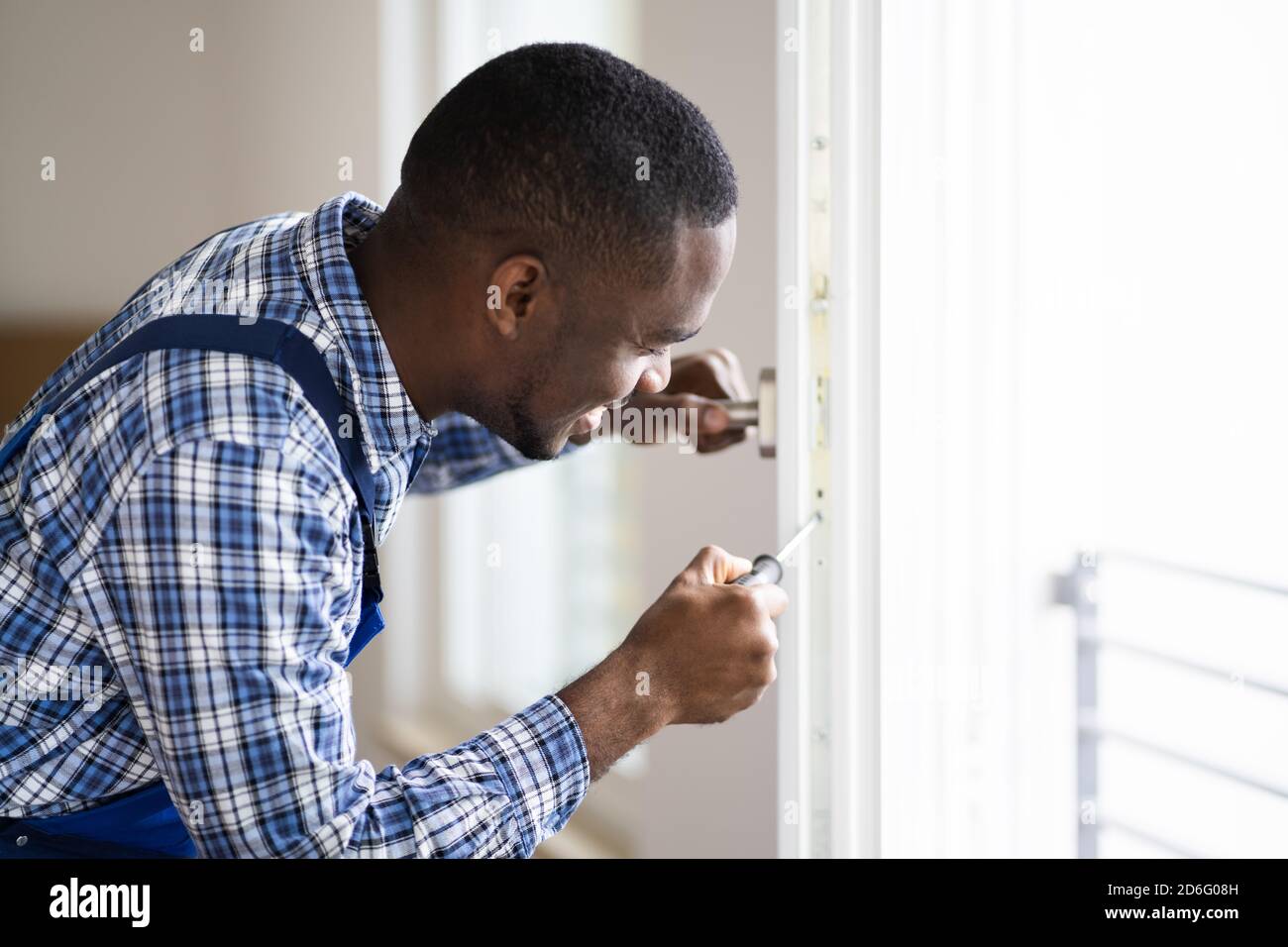 Junger Afrikanischer Reparateur In Overalls Fenster Installieren Stockfoto