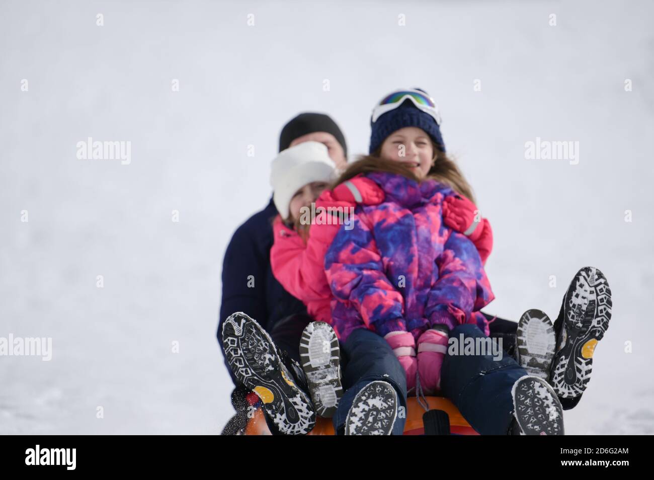 Glücklicher Familienvater mit zwei Mädchen, die auf Tubing reiten Weißer Schnee im Winterresort Stockfoto