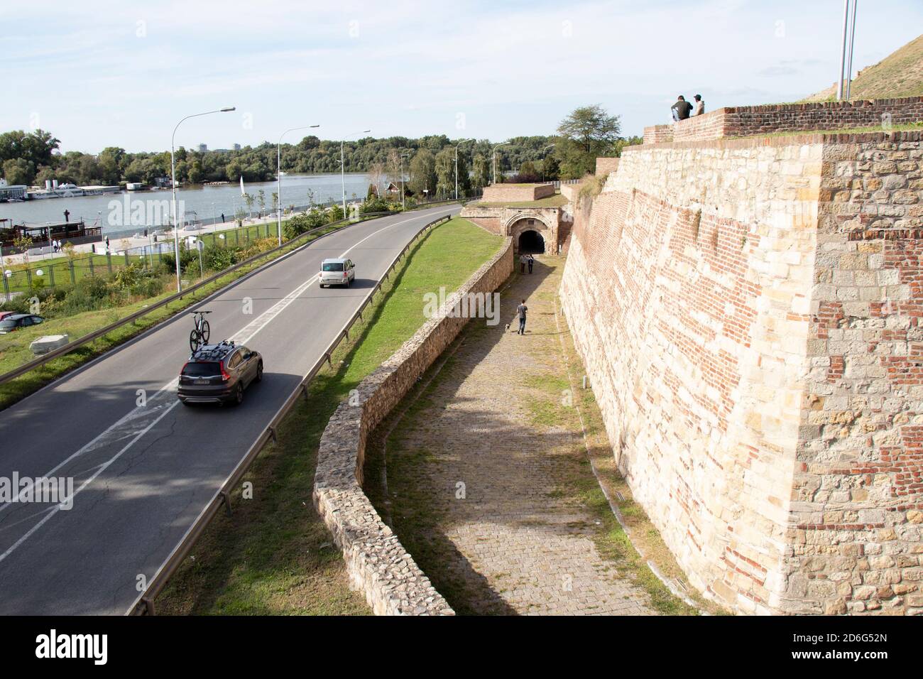 Belgrad, Serbien - 09. Oktober 2020: Menschen sitzen und gehen zu Fuß Weg der Festung Kalemegdan, Autos vorbei an der Straße und das Flusswasser Stockfoto
