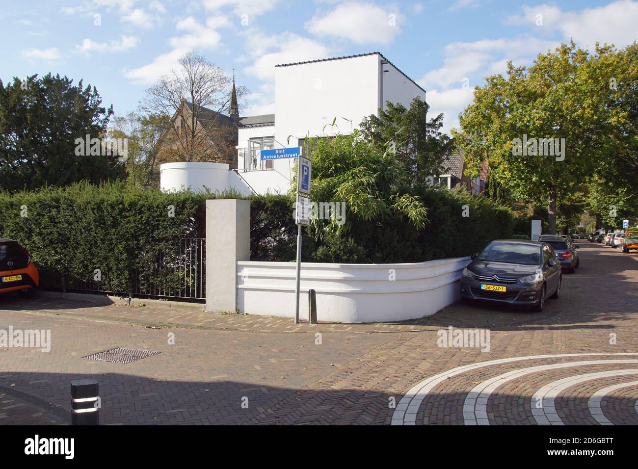 Weiß, Kubist, Arzthaus (1933) mit geraden horizontalen und vertikalen Linien mit dahinter die Kirche im niederländischen Touristenort Bergen. Stockfoto