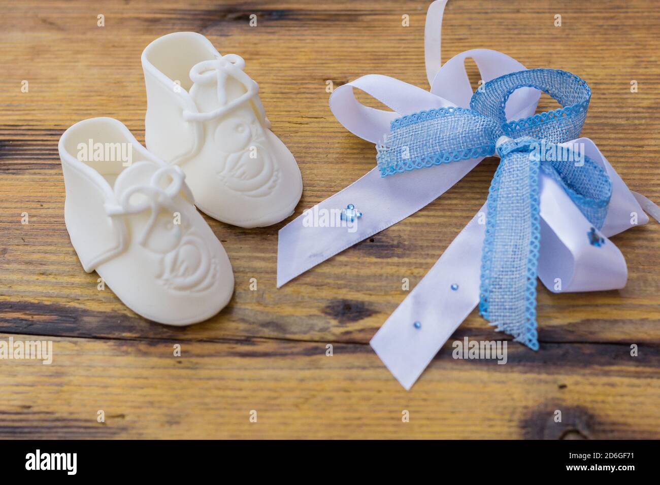Weiße Baby Stiefel mit blauer Schleife auf rustikaler Holzoberfläche, Gender Reveal Konzept Stockfoto