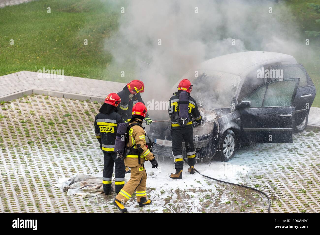 Warschau, Polen - 7. Juli 2020: Feuerwehr, die ein brennendes Auto  ausstellt. Rauchschwaden in der Nähe des Autos. Autofeuer auf dem  Parkplatz. Feuerwehrmänner haben die ausgestreut Stockfotografie - Alamy
