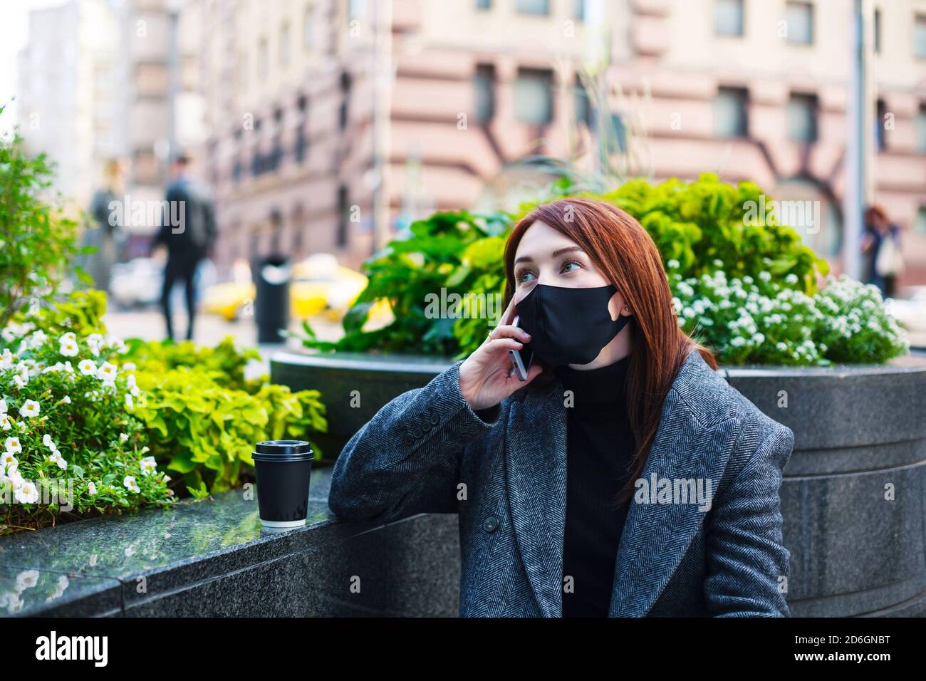 Rotschopf Frau in Schutzmaske reden auf einem Smartphone in der Innenstadt. Geschäft während des Coronavirus-Konzepts. Stockfoto