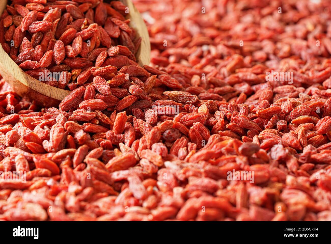 Trockene Goji-Beeren in einer kleinen Holzschüssel, verstreut auf dem Schreibtisch unten Stockfoto