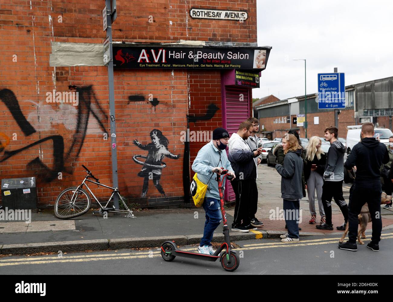 Nottingham, Nottinghamshire, Großbritannien. Oktober 2020. Ein Mann sucht sich ein Werk des Graffiti-Künstlers Banksy. Die Arbeit, außerhalb eines Schönheitssalons, zeigt ein Mädchen Hula-Hooping mit einem Fahrradreifen neben einem Fahrrad, das sein Hinterrad fehlt. Credit Darren Staples/Alamy Live News. Stockfoto
