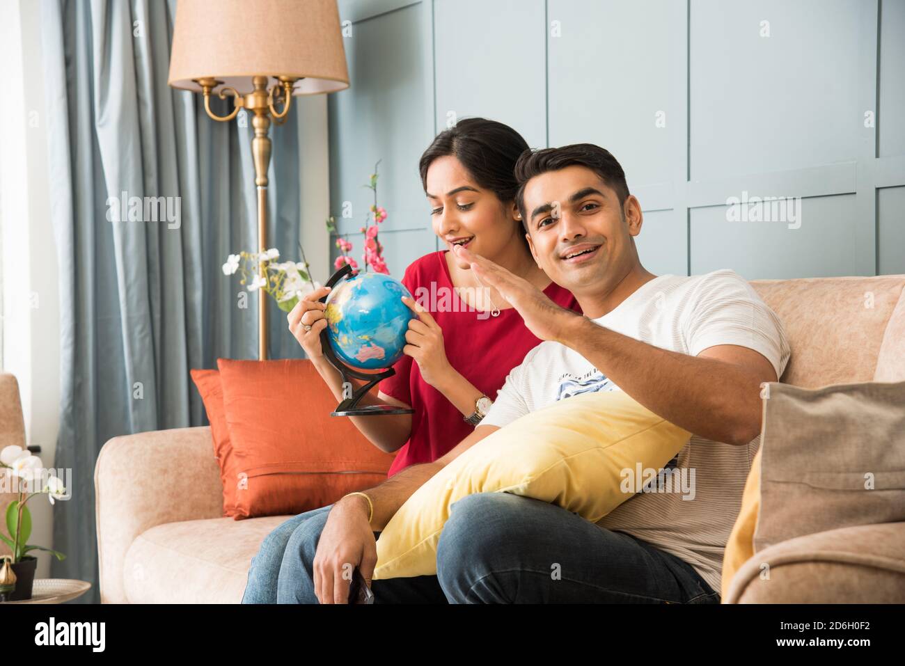 Reise- und Tourismuskonzept - Asiatisch indisches junges Paar Planung Urlaubsreise mit 3d Globe Modell, während Sie auf dem Sofa sitzen Oder Couch Stockfoto