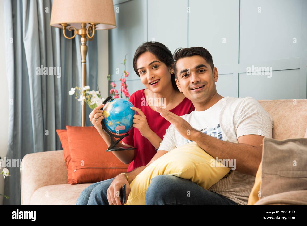 Reise- und Tourismuskonzept - Asiatisch indisches junges Paar Planung Urlaubsreise mit 3d Globe Modell, während Sie auf dem Sofa sitzen Oder Couch Stockfoto