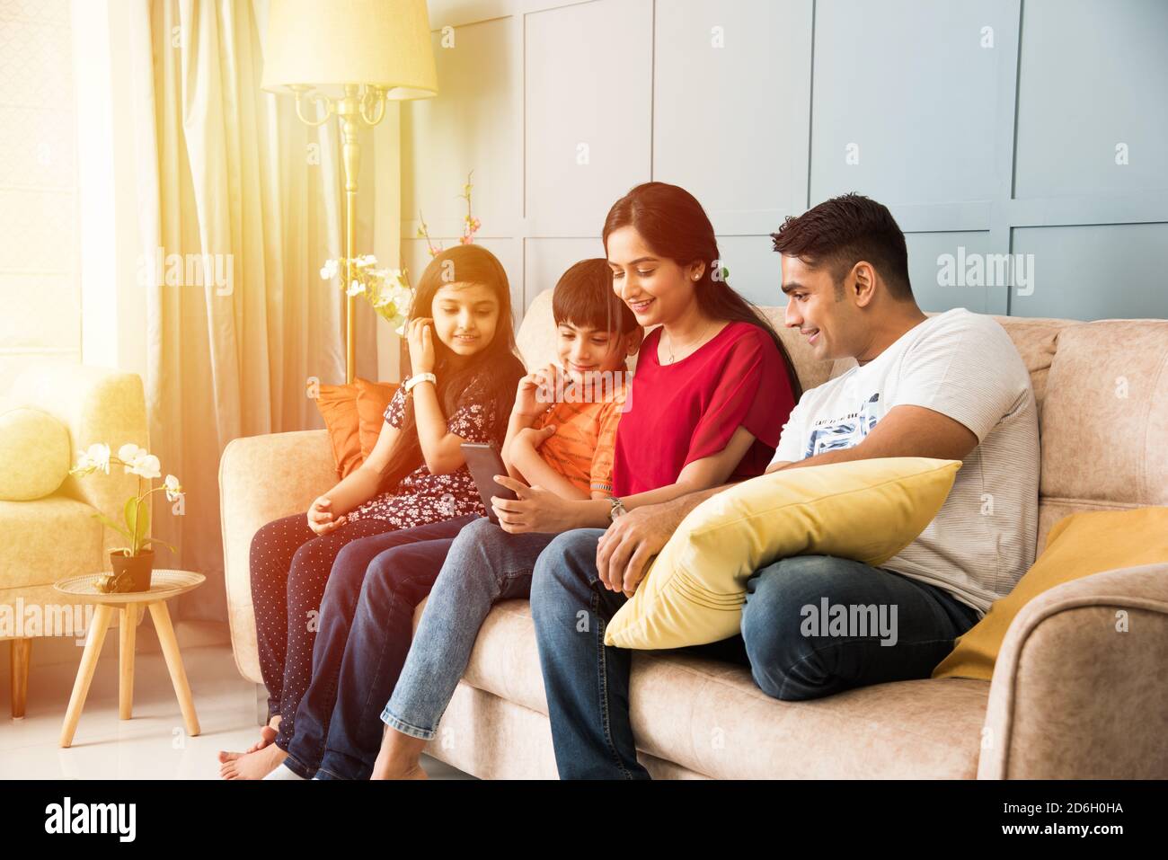 Indische Familie sitzt auf dem Sofa und mit Smartphone, Laptop oder Tablet, Film oder Surfen im Internet Stockfoto